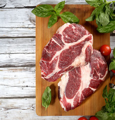 fresh raw meat, herbs and spices on a cutting board on a wooden background