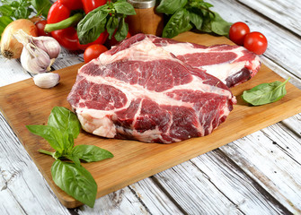 fresh raw meat, herbs and spices on a cutting board on a wooden background