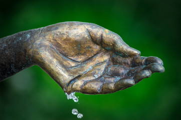 Messing Hand mit Wasser und gr&uuml;nem Hintergrund