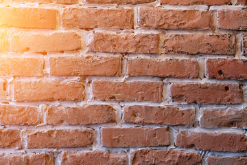 Texture of old red brick wall in rays of the sun