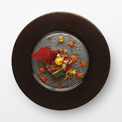 Veal tartare on black plate, isolated on white