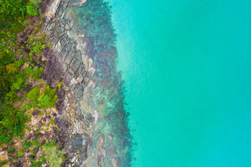Rocky sea beach turquoise clear water with green forest.
