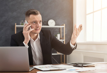 Young serious businessman talking on mobile phone