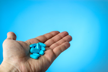 Blue pills in a patiens hands on blue background. Caring for the