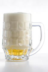 Beer mug. Mug of light fresh beer with a lot of foam on light ba