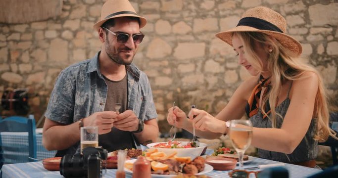 Young tourists couple having fun eating at traditional Greek restaurant