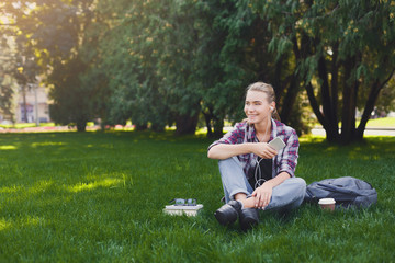 Young woman listening to music on grass outdoors