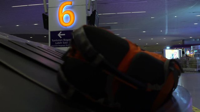 At the airport in the waiting room of luggage at the conveyor belt, man takes a backpack and leaves