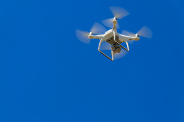 Drone with camera flying in blue sky