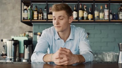 Portrait of a happy young bartender behind the counter