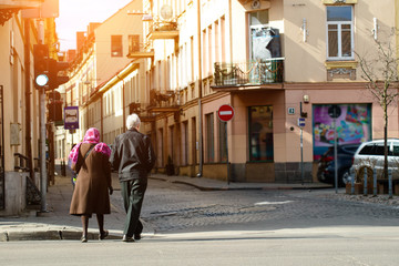 Fototapeta premium Unidentified people walking in old street of European town in ra