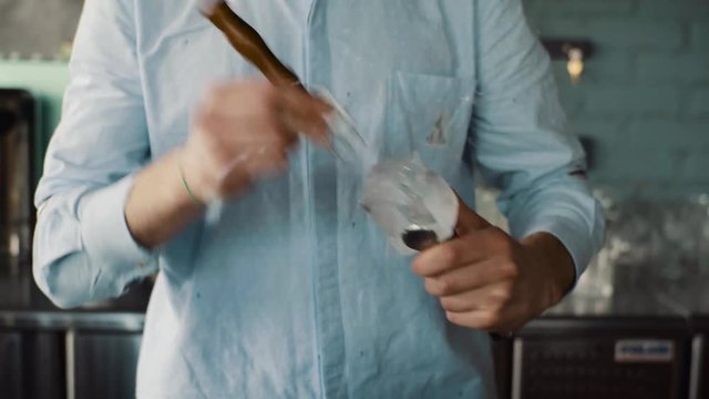 Bartender carves ice using ice pick