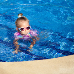 little pretty girl is swimming in pool,