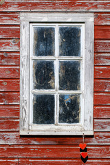 Barn window with rustic antique red hearts hanging from rope