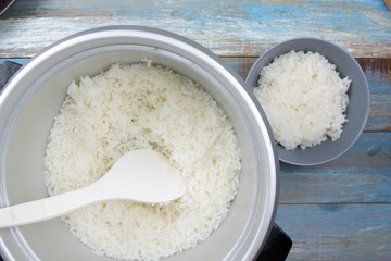 Cooked rice on plastic ladle in electric rice cooker