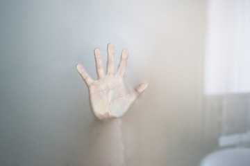Female hands behind the glass in the bathroom.