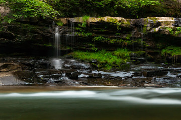A little waterfall with motion, large stones and green moss.