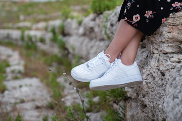 Female sneakers. White female shoes on feet. Sneakers closeup.