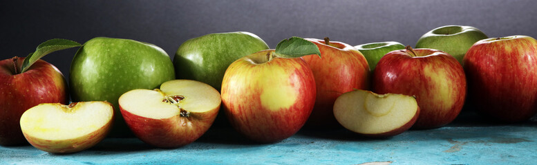 Ripe red apples with leaves on wooden background.