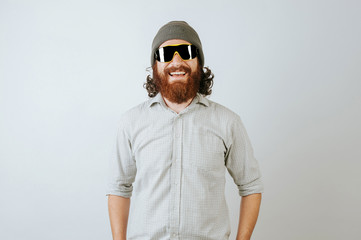 Funny curly bearded man wearing mountain glasses smiling at camera on white background.