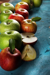 Ripe red apples with leaves on wooden background.