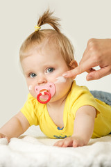 Studio portrait of adorable baby girl with cream on her cheeks
