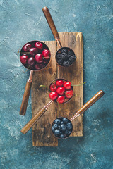 Different berries in copper measuring cups