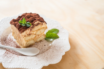 Italian tiramisu dessert on a porcelain plate on a wooden background