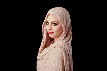 portrait of pretty girl wearing a pink headscarf. black studio background.