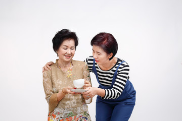 Senior woman drinking tea with her daughter take care, isolated on white background