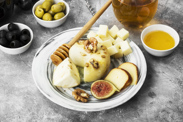 Snacks with wine - various types of cheeses, figs, nuts, honey, grapes on a gray background