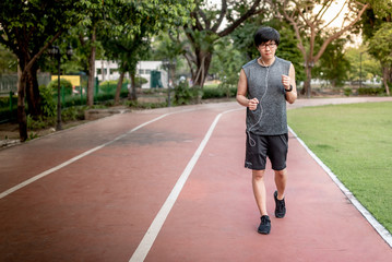 Young Asian man runner jogging on running track in the park