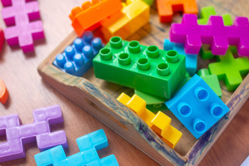 Toy colorful plastic blocks on wooden floor background