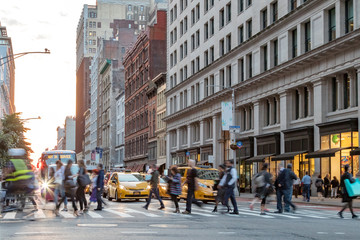 Fast paced street scene with people walking across a busy intersection on Broadway in Manhattan New York City