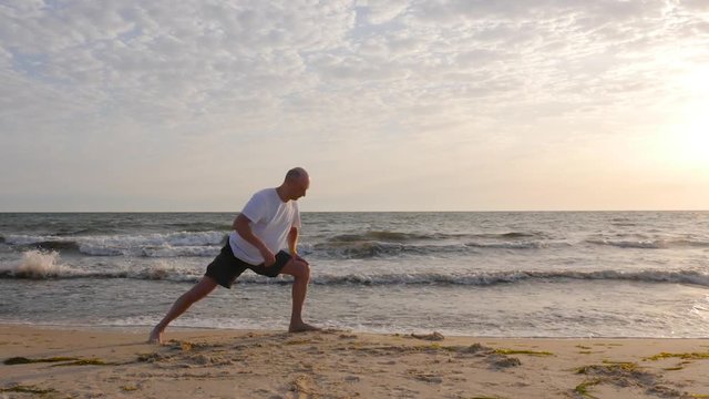 Sportive man practicing yoga asana on seashore at sunset
