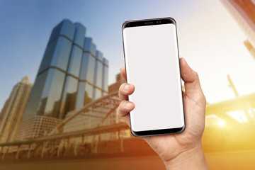 Hand holding blank screen smart phone with office buiding background