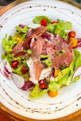 Smoked duck salad in white plate on the table.