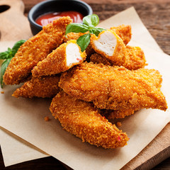 Delicious crispy fried breaded chicken breast strips with ketchup.
