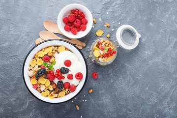 Obraz na płótnie Canvas Healthy breakfast. Fresh granola, muesli with yogurt and berries on gray background. Top view. Copy space.