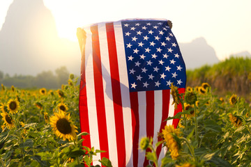 4th July United State Independence day concept by people is celebration with holding USA flag on the sunflower field.