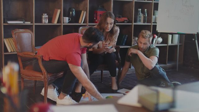 Creative businesspeople working with company strategy documents on office floor. Business professionals planning strategy on floor. Creative people planning startup business on floor in office