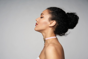 Fototapeta na wymiar Beauty closeup profile portrait of beautiful mixed race caucasian - african american woman wearing chocker with closed eyes, isolated on gray background