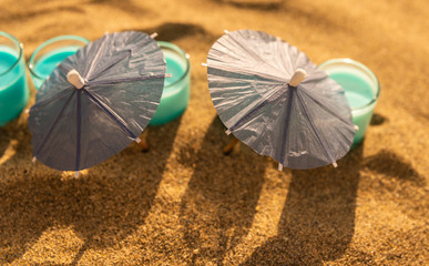 colorful shots drinks on a sandy beach with umbrellas for drinks