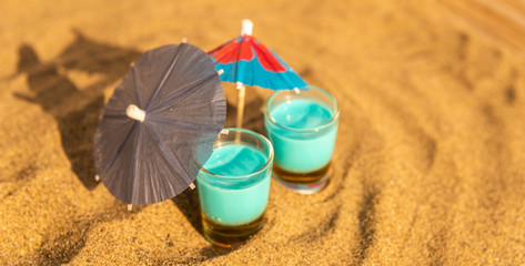 colorful shots drinks on a sandy beach with umbrellas for drinks