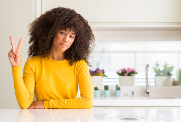 African american woman wearing yellow sweater at kitchen showing and pointing up with fingers...