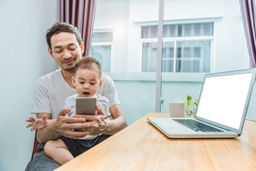 Asian father and son using smart phone together in home background. Technology and People concept. Lifestyles and Happy family theme. Internet and communication theme