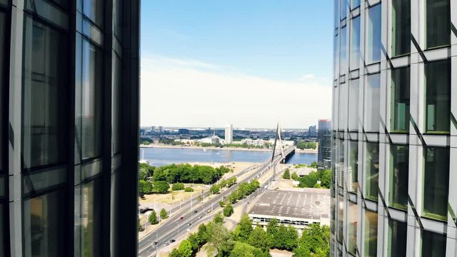 Aerial shot of skyscrapers in Riga, Latvia, cityscape on the background. The camera flying up the skyscrapers facade. Twin glass office buildings, highway and bridge on the background