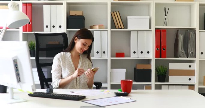 businesswoman in white blouse smiling and using smartphone.