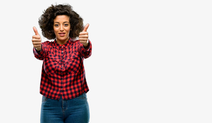 Beautiful arab woman stand happy and positive with thumbs up approving with a big smile expressing okay gesture