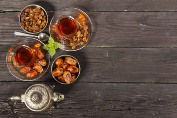 Traditional Arabic, Turkish Ramadan tea with dry dates and raisins on a wooden black table. Ramadan. Turkish fresh tea with dates. View from above.
